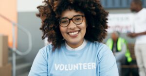 Volunteer woman, portrait and happy for charity, clothes drive and community service with kindness